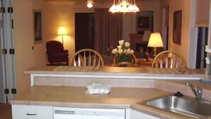 A compact kitchen with a dishwasher, a sink, and a small dining area with chairs and a table.