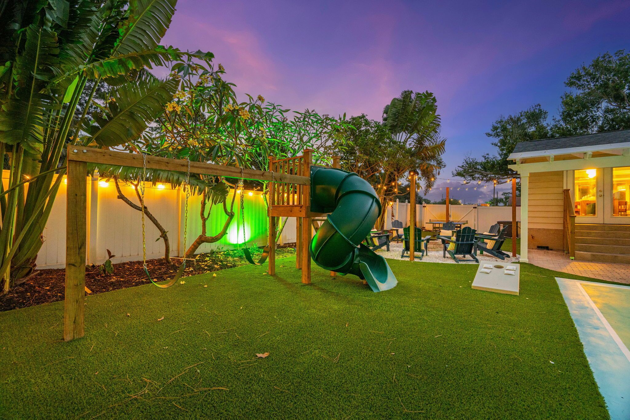 A playground with a slide, swings, and artificial grass.