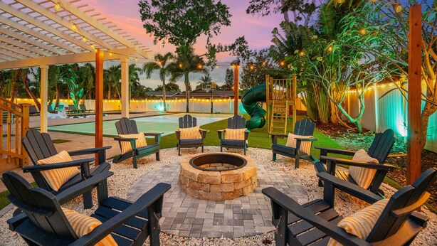 Un espacio al aire libre con sillas Adirondack, una chimenea y una piscina.
