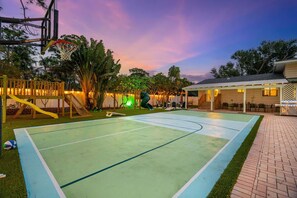 A basketball court with a hoop, a slide, and a pool area.