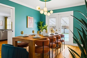 A dining area with a wooden table, six chairs, and a chandelier.