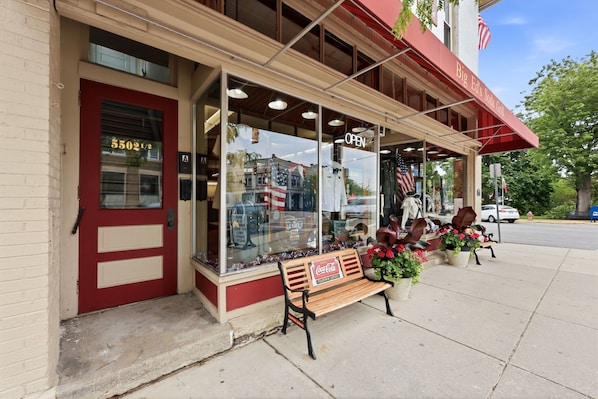 A storefront with a red door, a bench, and American flags.