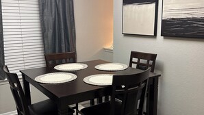Un coin repas avec une table en bois foncé, quatre chaises et un tapis.