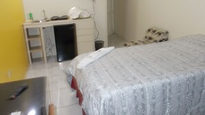 Une chambre à coucher avec un lit, un bureau avec un ordinateur, une télévision et une chaise.