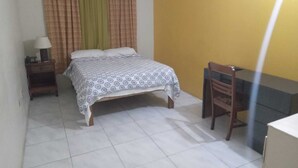 Une chambre à coucher avec un lit, une table de chevet, une chaise et un bureau.