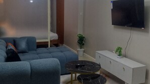A living room with a sofa, a small round table, a TV mounted on the wall, and a cabinet. - Tranquil 1-bedroom house perfect for a relaxing Nairobi getaway (Nairobi)