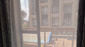 A hotel room with a bed, a window with a view of a building and outdoor furniture. - Tranquil 1-bedroom house perfect for a relaxing Nairobi getaway (Nairobi)