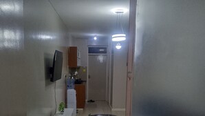 A room with a bed, a small table, a sofa, a TV mounted on the wall, and a kitchenette area. - Tranquil 1-bedroom house perfect for a relaxing Nairobi getaway (Nairobi)