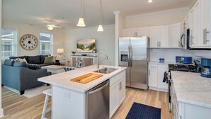 Een moderne keuken met een centraal eiland, roestvrijstalen apparatuur en witte kastjes.
