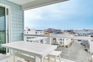 A balcony with a white table and chairs, overlooking a parking lot and buildings with cranes. - Beach Block Beauty w/ Pool (Wildwood)