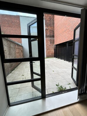 A view through a glass door into a courtyard with a brick wall and a metal fence. - Apartment in Birmingham JQ Area Free WiFi & Parking.  (Birmingham)