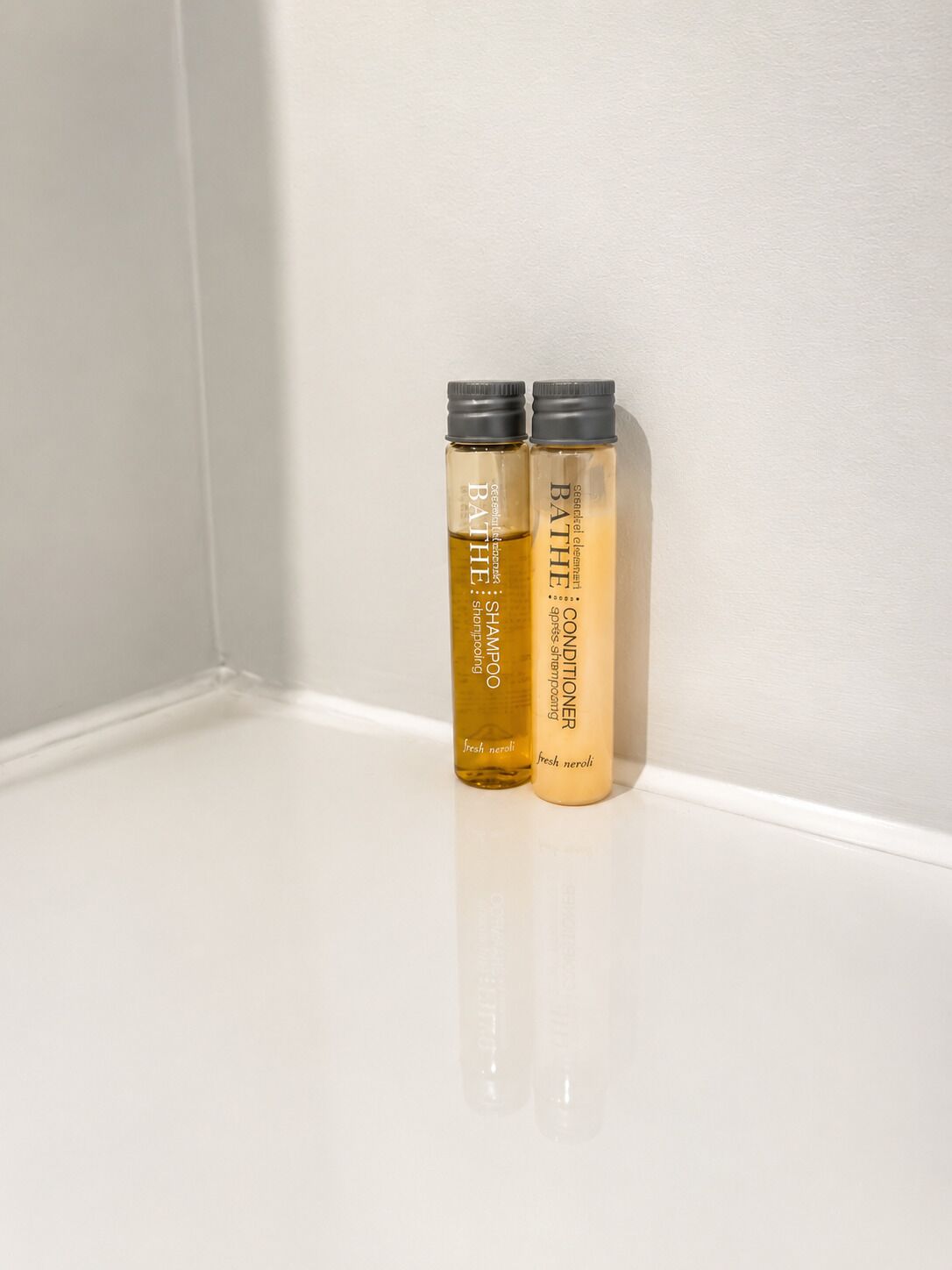 Zwei Flaschen BATHÉ Shampoo und Conditioner auf einer weißen Oberfläche.