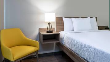A hotel room with a bed, a nightstand with a lamp, and a yellow chair.