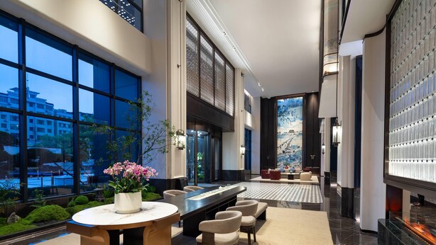 Eine moderne Lobby mit Sitzgelegenheiten, einem großen Fenster und einer Wandverkleidung.