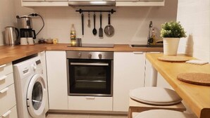 Een kleine keuken met een wasmachine, oven en een houten aanrecht.