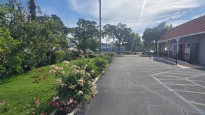 A parking lot with a building labeled 'LAGUIOLE INN' and a garden with flowers.