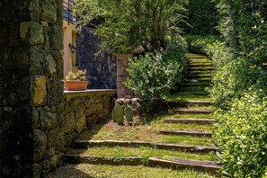 Eine Steintreppe führt zu einem Gebäude, links steht ein Blumentopf.