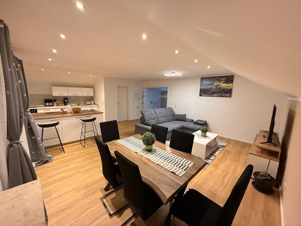 A modern apartment with a dining area, kitchen, and living space.