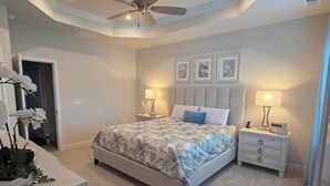 A bedroom with a bed, two bedside tables, a ceiling fan, and a door leading to another room. - Coastal Luxury Townhome in West Ocean City, 4 Bedrooms , Near Beach, Assateague (Berlin)
