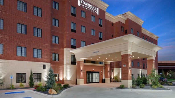 Un hotel Staybridge Suites con fachada de ladrillo, múltiples ventanas y entrada cubierta.