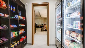 Un pasillo que conduce a un comedor con un sofá y sillas, flanqueado por estantes para aperitivos y un refrigerador de bebidas.