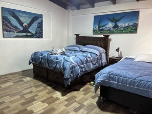 Une chambre avec deux lits, un plancher en bois et deux tableaux accrochés aux murs.