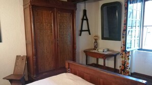 A bedroom with a wooden bed, a dresser, a mirror, and a window with curtains. - Country house with swimming pool  (Savenès)