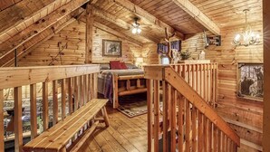A wooden cabin with a loft bedroom, a wooden staircase, and a window with a bear view. - Cozy 2-bedroom cabin in beautiful Sevierville with fishing pond (Sevierville)