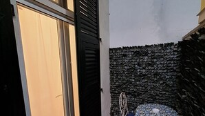 A small patio with a metal table and chairs, a black door, and a textured wall. - Manarola Sunset House | 2 Bathrooms | In the Heart of Cinque Terre (Manarola)