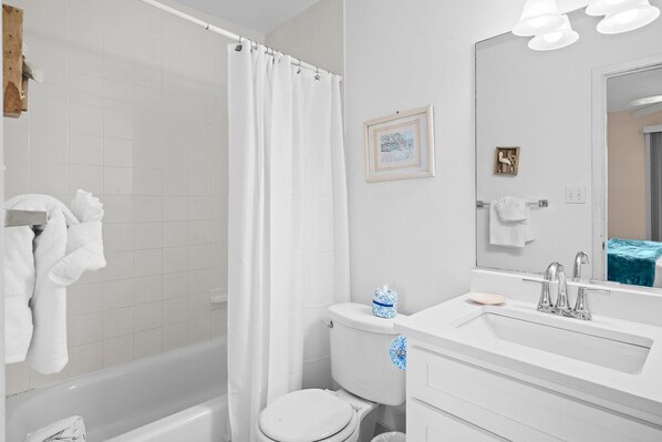 Een badkamer met een bad, toilet, wastafel en spiegel.