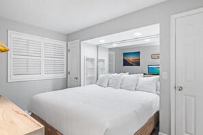 A bedroom with a large bed, a bedside table, a mirror, and a wall-mounted TV. - Sundestin 1511 (Destin)