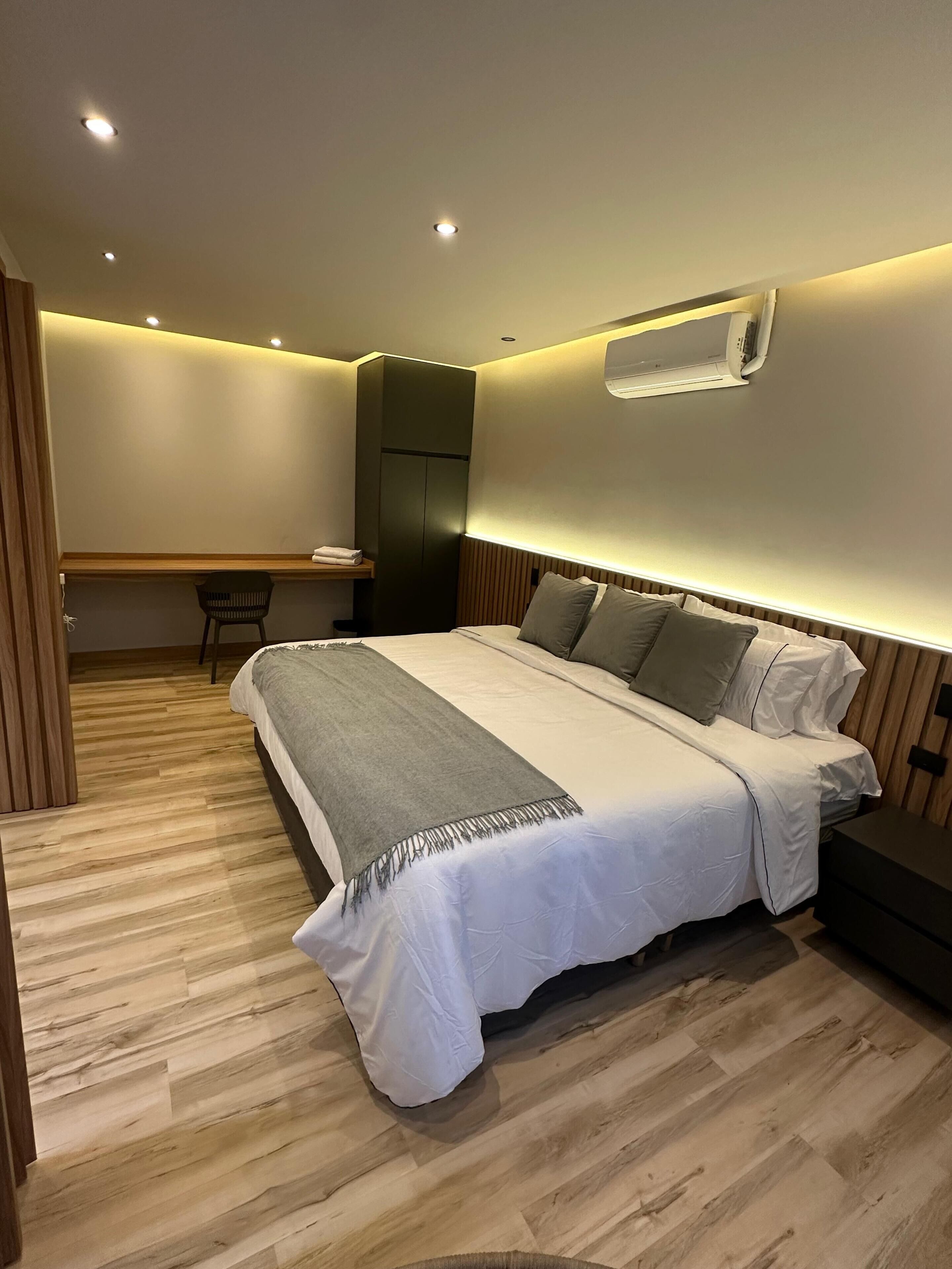 Un dormitorio con cama, mesita de noche y escritorio.