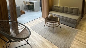 Una sala moderna con un sofá, una mesa de centro redonda y una silla de mimbre.