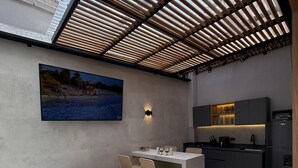 Una cocina moderna al aire libre con barra, bañera de hidromasaje y comedor con sillas.