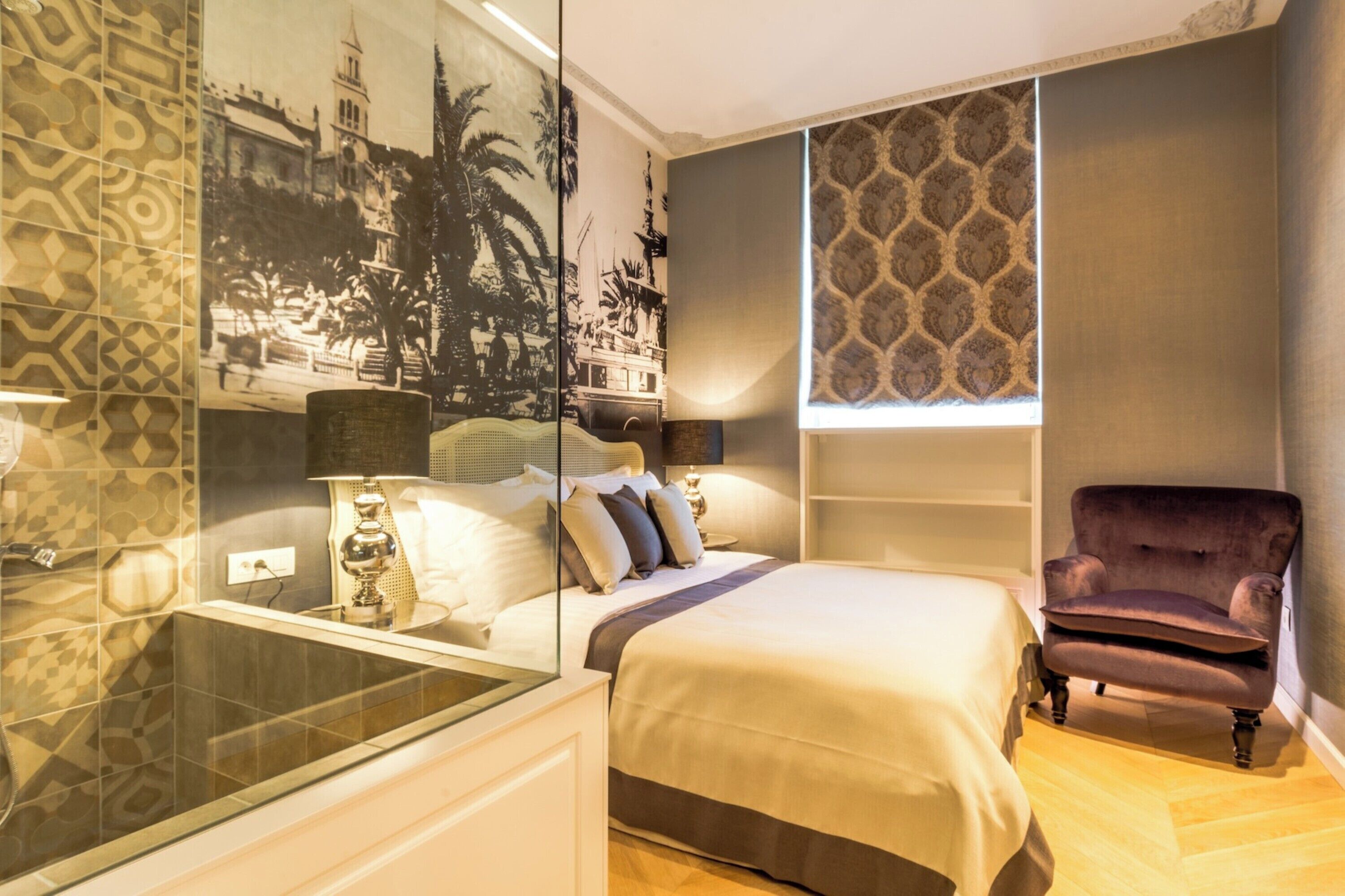 Un dormitorio con cama, una silla, un espejo y un papel tapiz estampado.