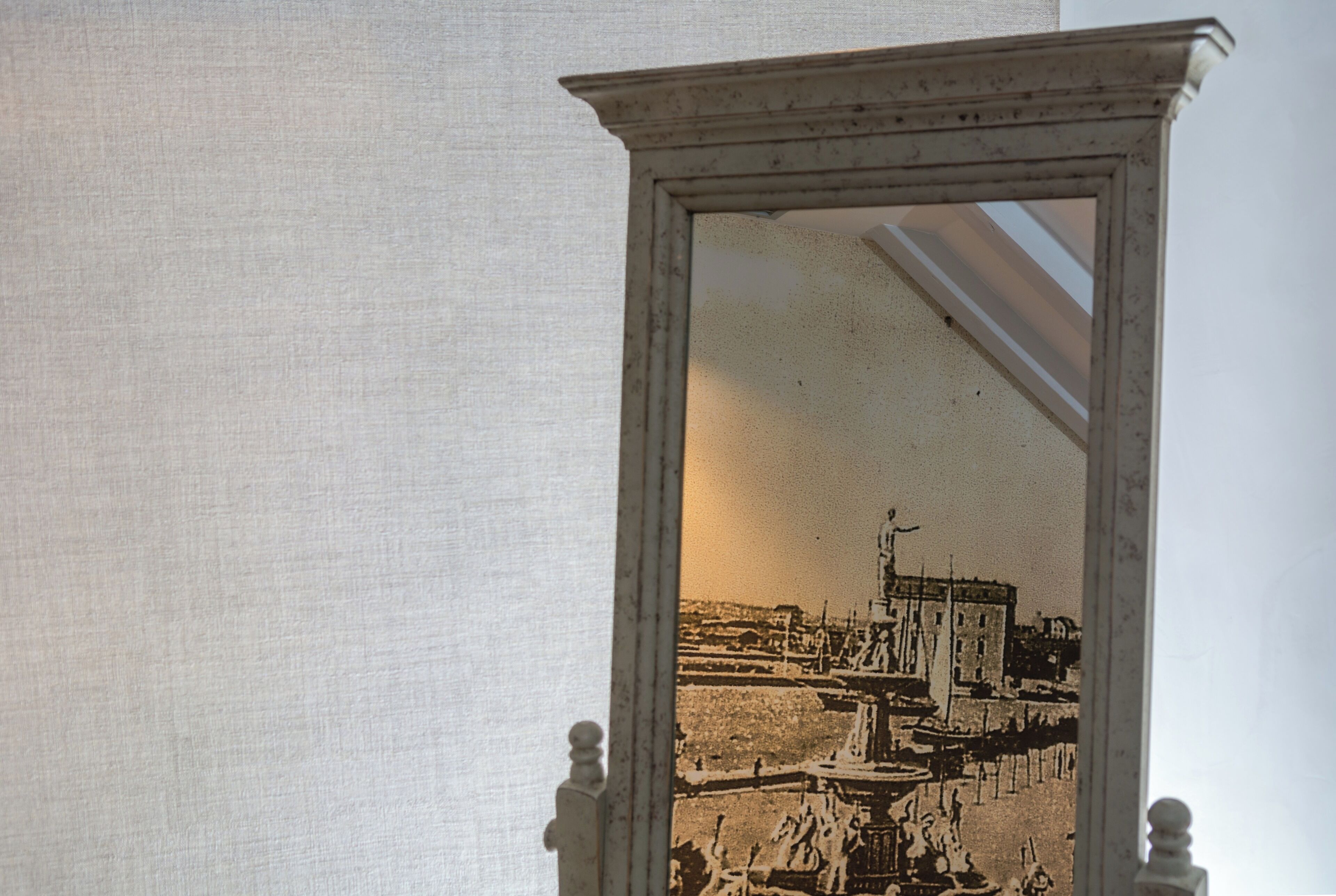 A mirror with a reflection of a building and a fountain.