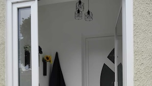A modern entrance with a glass door, a wooden bench, a black coat hanging, and a geometric wall design. - Sea and Mountains, comfortable country house full of charm 6 minutes from the sea (Ventiseri)