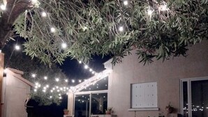 An outdoor patio area with string lights, a covered seating area, and a potted plant. - Sea and Mountains, comfortable country house full of charm 6 minutes from the sea (Ventiseri)