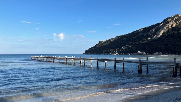 A coastal scene with a wooden pier extending into calm waters, a sandy beach, and a hill with rocky outcrops. - Sea and Mountains, comfortable country house full of charm 6 minutes from the sea (Ventiseri)