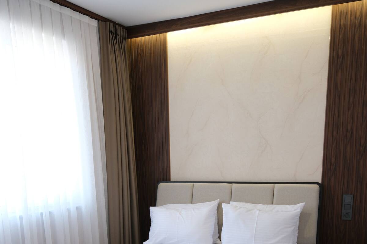 Una cama bien hecha con ropa de cama y toallas blancas, un cabecero de madera y un suelo de madera.