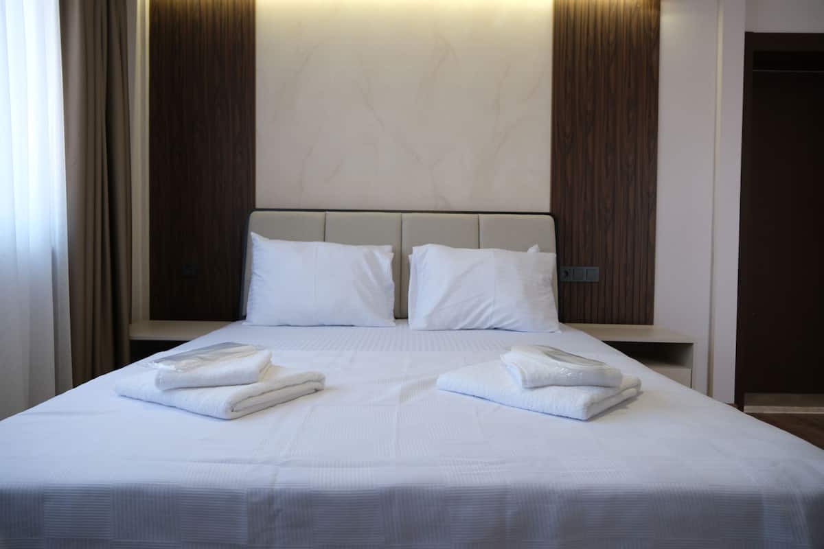 Una habitación de hotel con una cama grande, dos almohadas y dos toallas dobladas con cuidado.