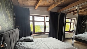 Een slaapkamer met een bed, een raam en uitzicht op een brug.