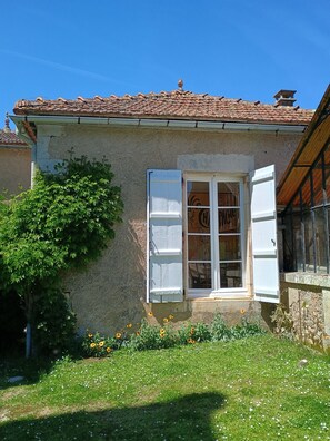 A house with a tiled roof, a window with shutters, and a garden with flowers. - Villa Paignon Studio, charming fully equipped cottage (Montbron)