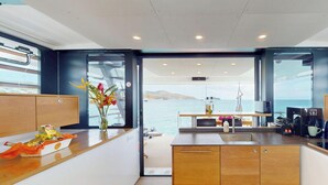 Een moderne keuken met uitzicht op zee, houten kastjes en een bloevas.