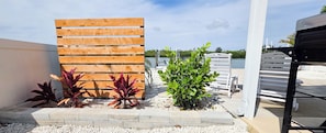A wooden fence, a small garden with plants, and a body of water in the background.