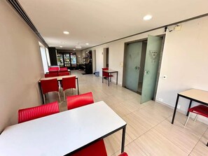 A dining area with tables and chairs, a vending machine, and a door leading to another room. - Le Premier Suites (São Paulo)