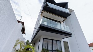Ein modernes, mehrstöckiges Gebäude mit Balkon, großen Fenstern und heller Fassade.