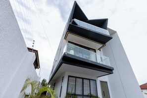 Ein modernes, mehrstöckiges Gebäude mit Balkon, großen Fenstern und heller Fassade.