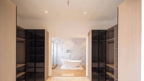 Ein modernes Badezimmer mit freistehender Badewanne, integrierten Regalen und Marmorwänden.