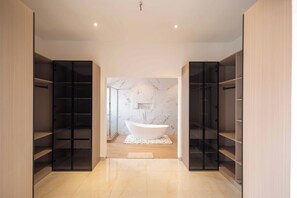 Ein modernes Badezimmer mit freistehender Badewanne, integrierten Regalen und Marmorwänden.